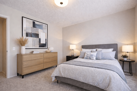 A bedroom with a large bed and a wooden dresser.