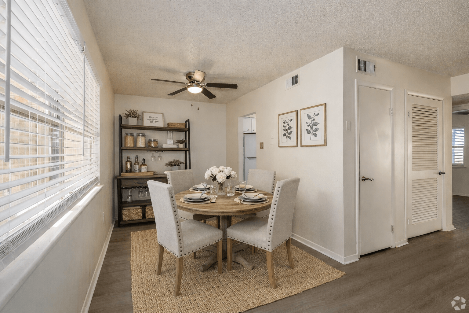 A dining room with a table set for two and a ceiling fan.