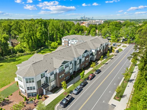 A large apartment complex is situated on a tree-lined street.