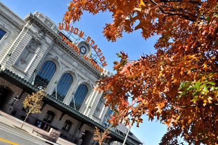 a building with a clock on it and a tree with orange leaves