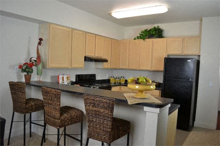a kitchen with a counter with three chairs