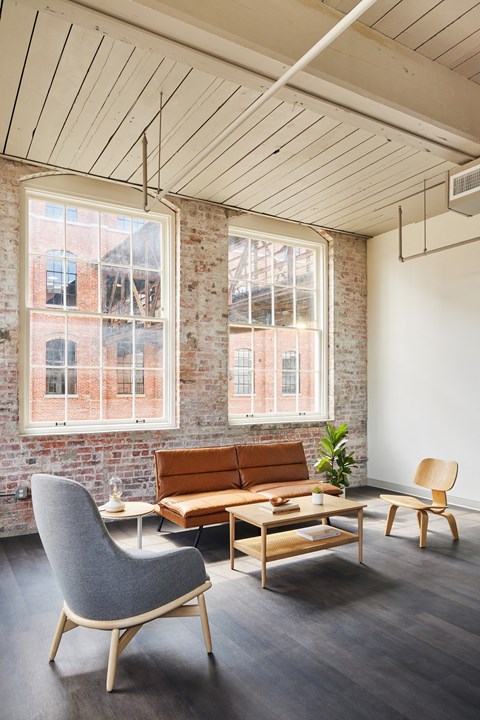 a living room with a couch and chairs and a brick wall at The Mill at Prattville, Prattville, 36067