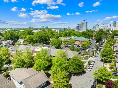 A suburban area with houses and trees in the foreground and a city skyline in the background.