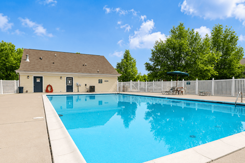 A small pool in a backyard with a white fence.