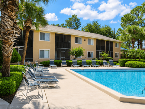A pool area with chairs and a building in the background.