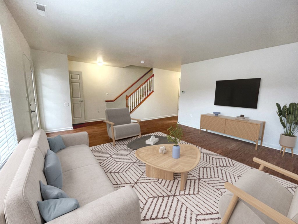 A living room with a grey couch, a wooden coffee table, and a TV on the wall.