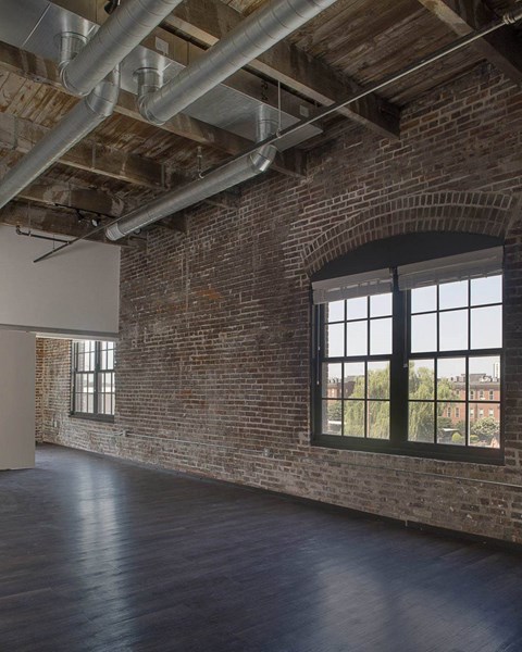 A large empty room with a brick wall and a large window.at South Main Artspace Lofts, Memphis, TN 38126