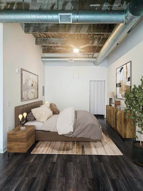 A bedroom with a bed, nightstand, and a plant.at South Main Artspace Lofts, Memphis Tennessee