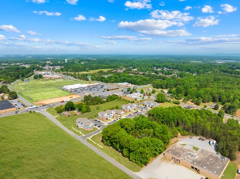 A bird's eye view of a small town with a large green field in the foreground.