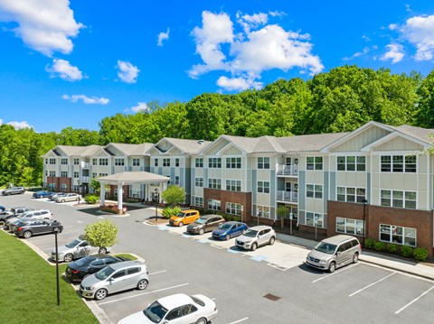 A parking lot in front of a large building with cars parked.