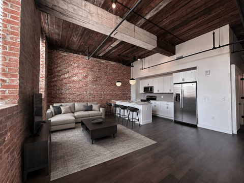 A modern kitchen and living room with a brick wall.