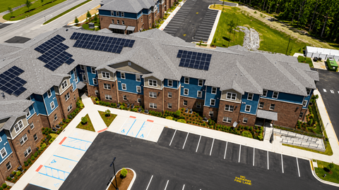 A parking lot in front of a building with solar panels on the roof.