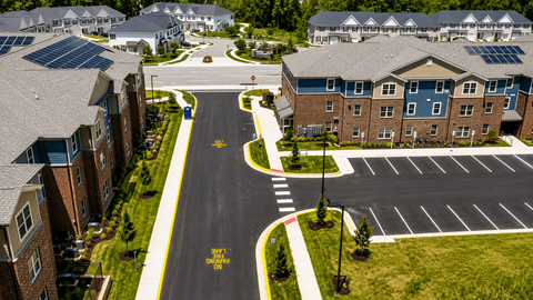 A road with a yellow sign that says "STOP HERE ON RED" in front of apartment buildings.