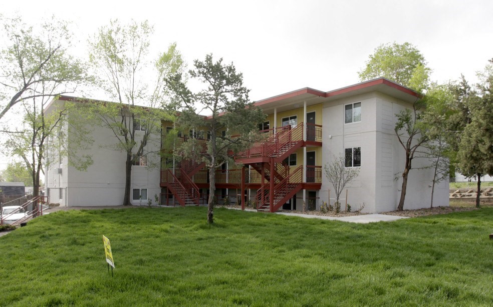 an apartment building with a green lawn and trees