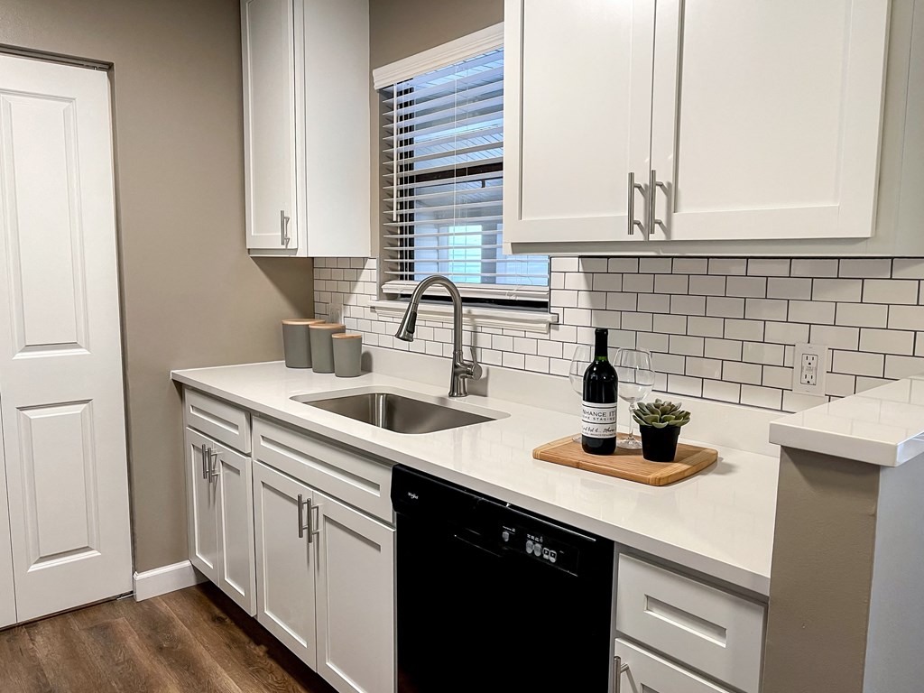 a kitchen with white cabinets and a sink and a window