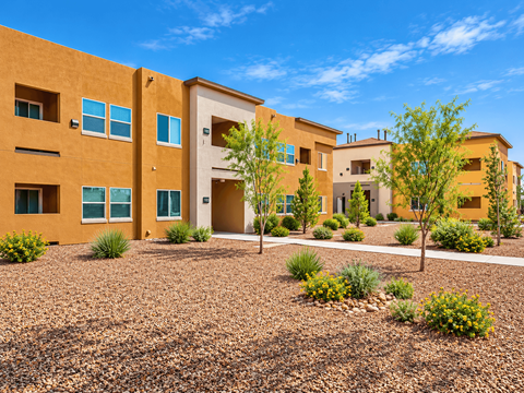 A building with a brown facade and a gravel courtyard in front.