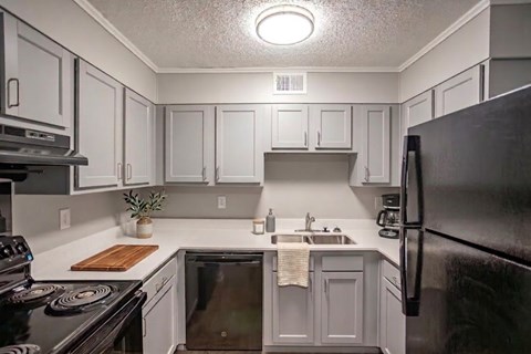 A kitchen with black appliances and white cabinets.
