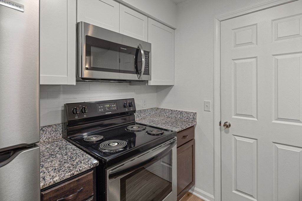 A kitchen with a stove, microwave, and refrigerator.at Mammoth at the Orchard Apartments, Rogers  