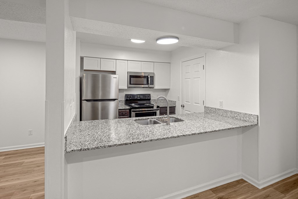 A kitchen with a granite countertop and stainless steel appliances.at Mammoth at the Orchard Apartments, Arkansas, 72756
