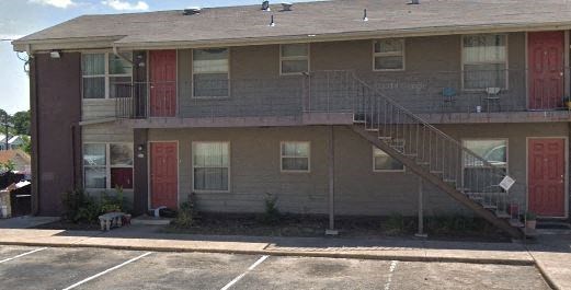 Apartment building with a red door and a staircase.