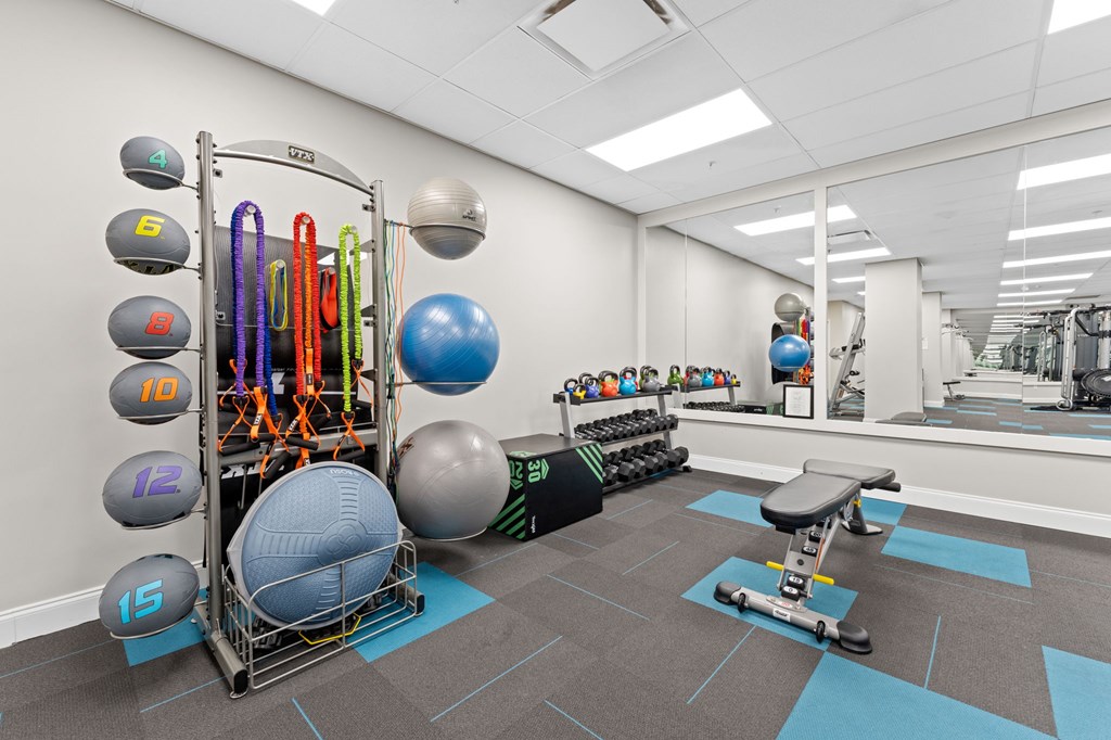 A gym with a variety of equipment including a weight rack, exercise balls, and a bench press.