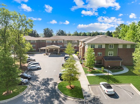 A sunny day at a residential complex with cars parked in the lot.