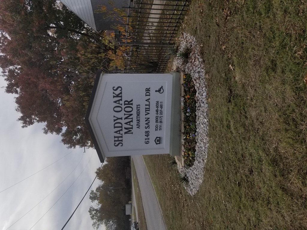 A sign for Shady Oaks Manor is displayed on a grassy area.