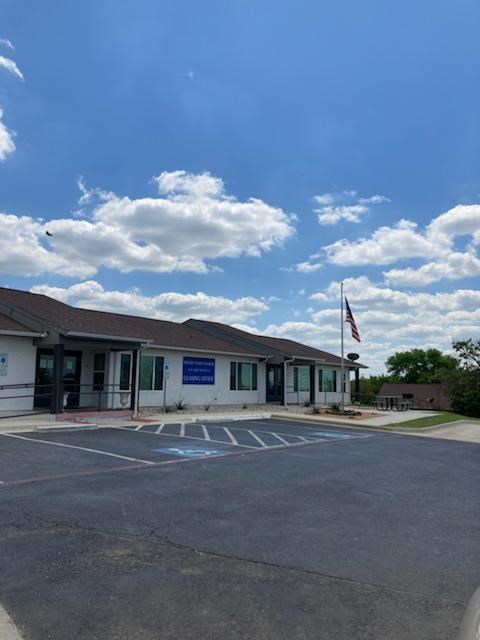 A building with a flag on top and a parking lot in front.