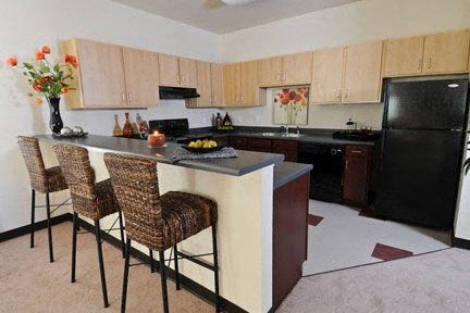 a kitchen with a bar with three chairs