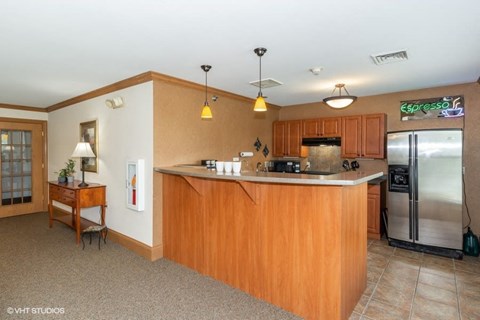 A kitchen with wooden cabinets and a countertop with a sink and a refrigerator.