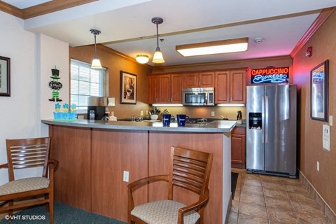 A kitchen with wooden cabinets and a counter with two chairs.