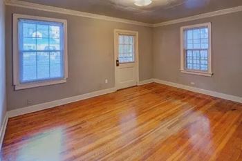 A room with wooden floors and two windows.
