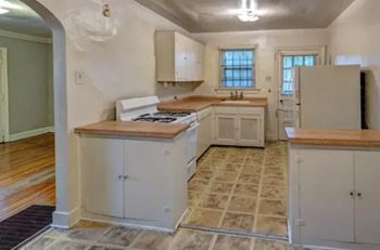A kitchen with white cabinets and a wooden countertop.