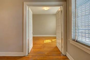 A hallway with a wooden floor and white walls.