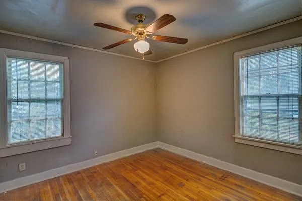 A room with a ceiling fan and two windows.