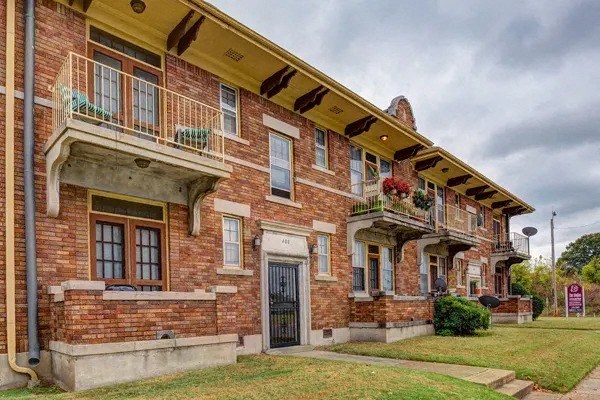 A red brick building with a balcony and a black door.