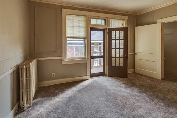 A room with a window, a door, and a carpeted floor.