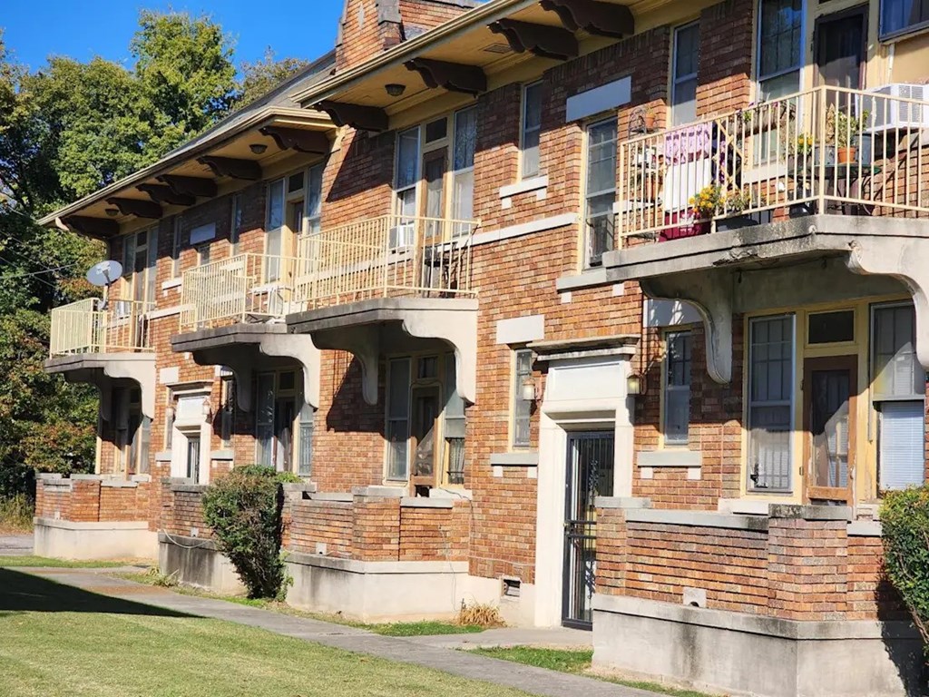 A row of red brick apartment buildings with balconies.