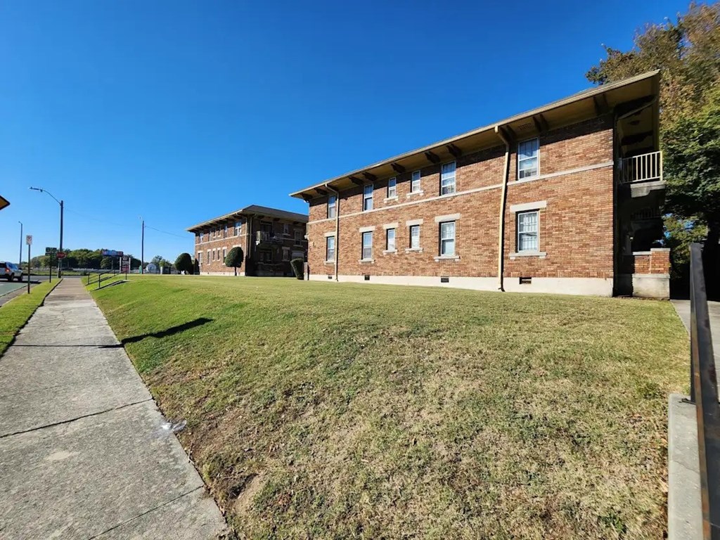 A brick building with a green lawn in front.