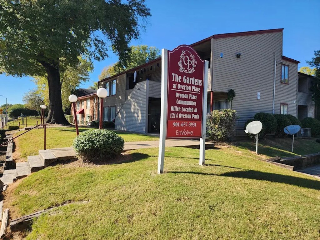 A sign for The Gardens at Overton Place stands in front of a building.