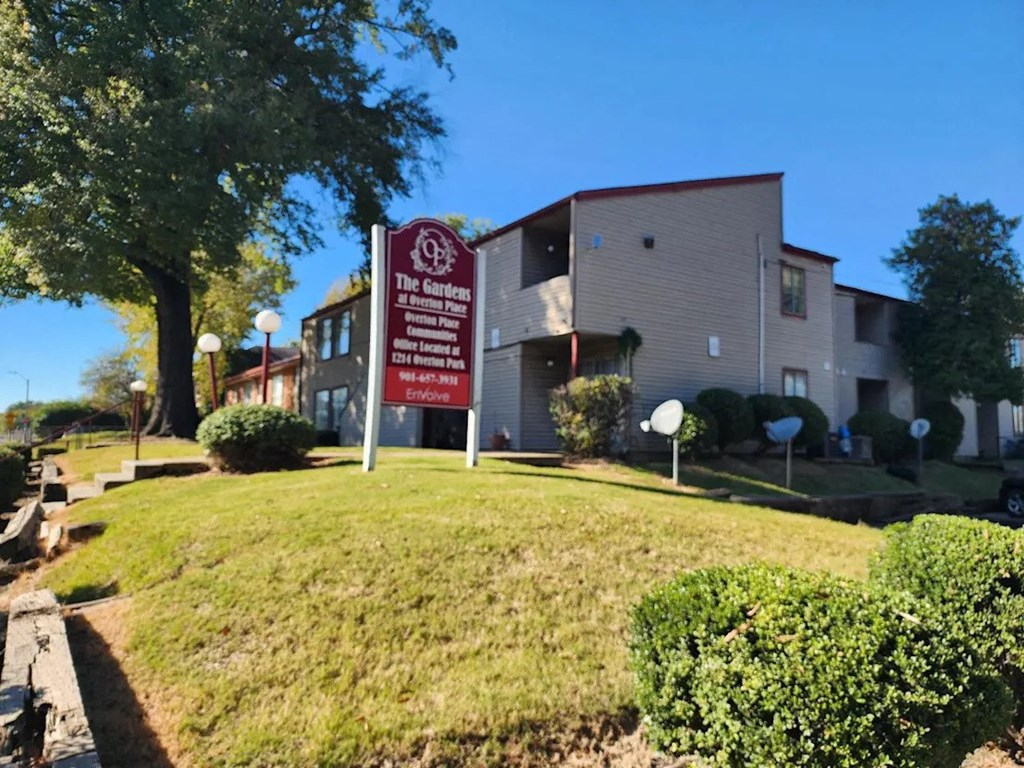 A sign for The Gardens at Crestmoor Park in front of a building.