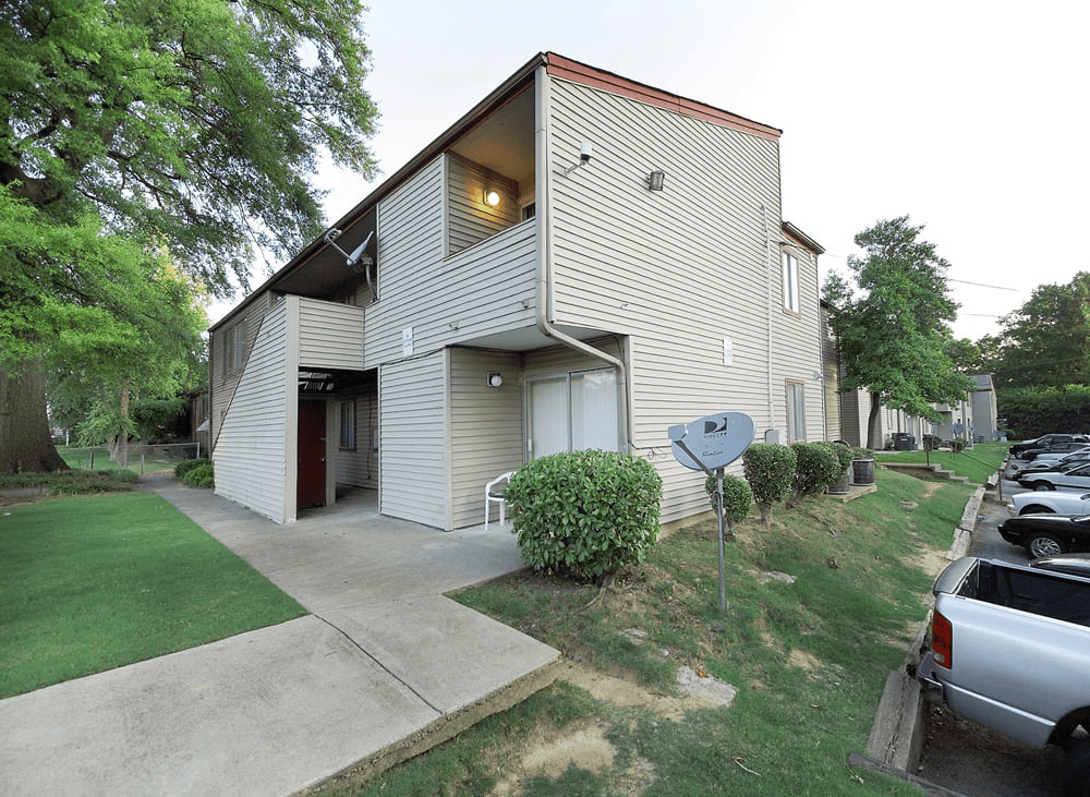 A house with a grey siding and a brown roof with a garage door.