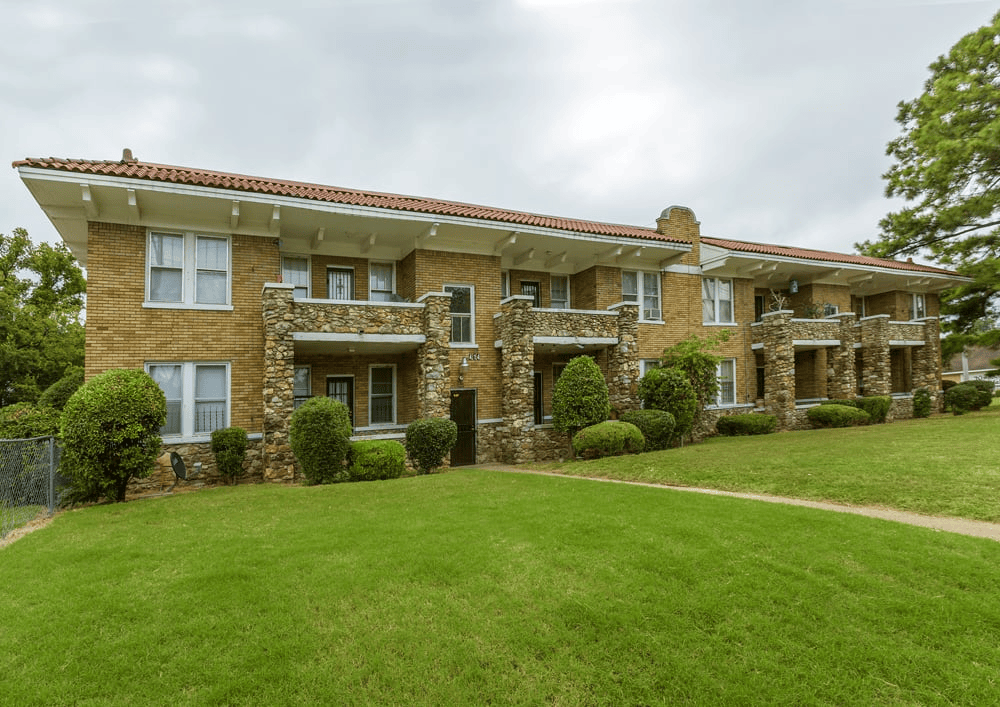 A large house with a red tile roof and stone pillars.