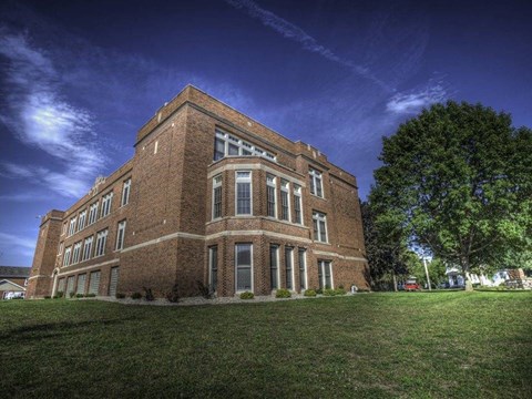 A large red brick building with a green lawn in front.