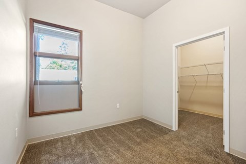 A room with a carpeted floor, a window, and an open door.