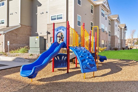 A playground with a blue slide and a red and yellow climbing structure.