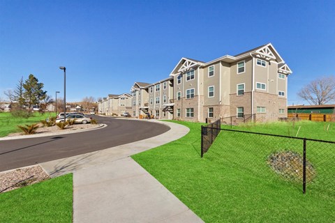 Apartment complex with a green lawn and a walkway.