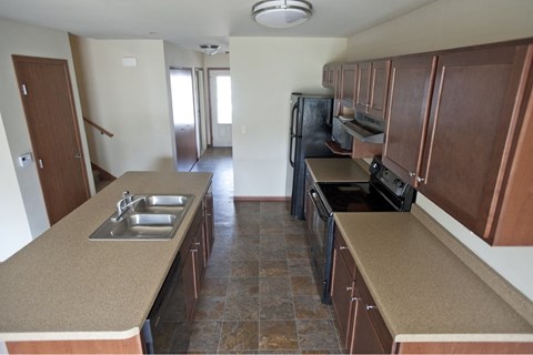 A kitchen with brown cabinets and a black refrigerator.