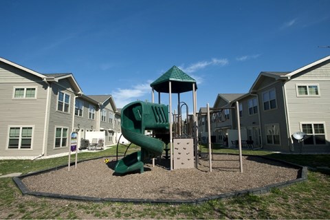 A playground with a green slide and a green canopy.