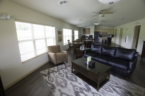 A living room with a black leather couch and a coffee table.